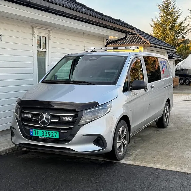 Grå varebil foran hvitt hus